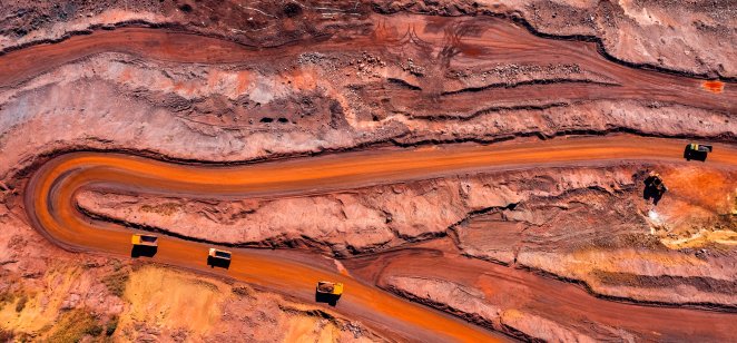 An aerial view of an open pit iron ore mine with heavy construction equipment 