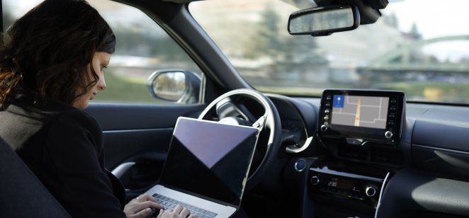 woman working on her laptop while car drives 