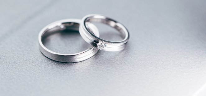 Two platinum band rings on a plain silver background