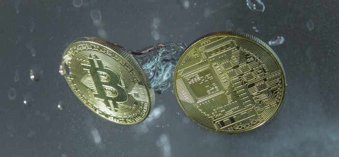 Two golden bitcoins fall into a tank of water
