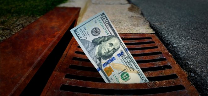 US 100 Dollar banknote down the street storm drain