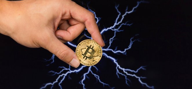 Man holding bitcoin gold coin in front of lightning 