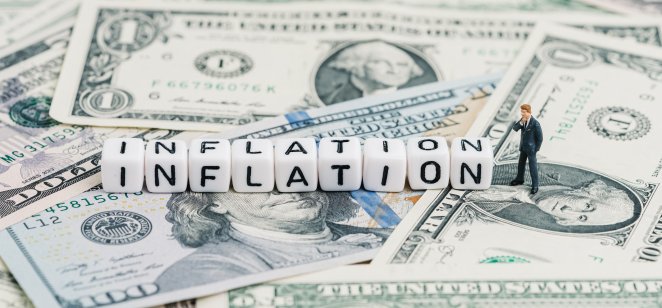Investing during inflation: Where to hide? Miniature people businessman standing and wise thinking with cube block combine word Inflation on US dollar money banknote using as economic inflation that money buys less than prior periods.