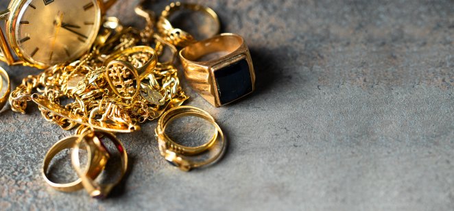 An assortment of gold jewellery lying on a grey background 