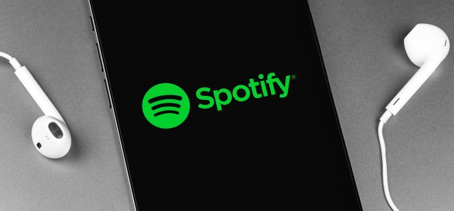 Spotify stock forecast: Can the streaming giant recover? Spotify logo mobile app on screen smartphone iPhone with EarPods headphones.