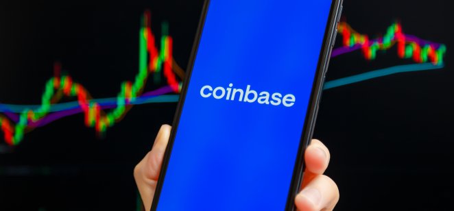 Coinbase app on a mobile phone, candle charts on the background