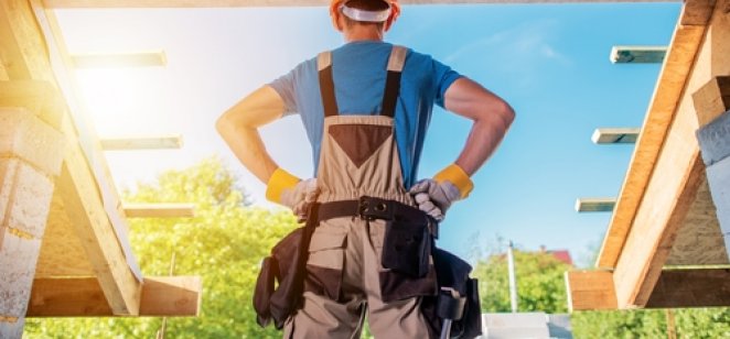 Will housebuilders benefit from a strong market in 2022? A housebuilder standing, hands on hips, looking at a project