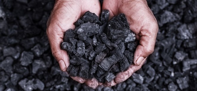 A coal miner holding pieces of coal