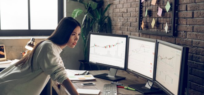 Female trader at a desk with market screens