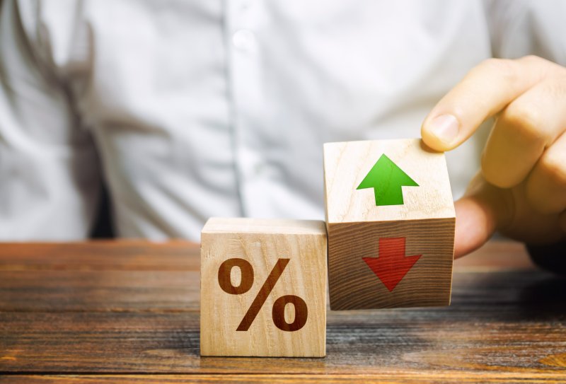 How do interest rates affect the stock market A businessman holds wooden blocks with percentages and up or down arrows. Mortgage and loan rates. Interest rate, shares, rating. The concept of business and finance.