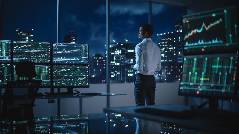 Financial trader A financial trader surrounded by multiple screens
