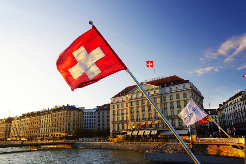 how to invest in swiss stocks Flag of the Geneva Canton and flag of Switerland in the city center of Geneva on the Mont Blanc Bridge