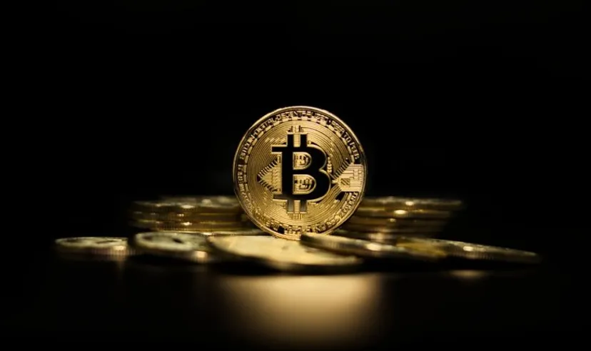 Representación de tokens físicos de Bitcoin sobre fondo negro.