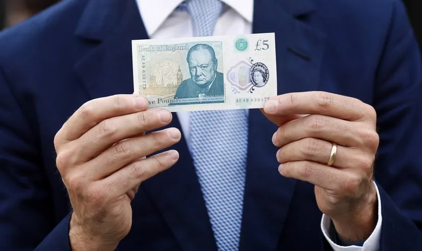 Suited businessman holding a five pound note