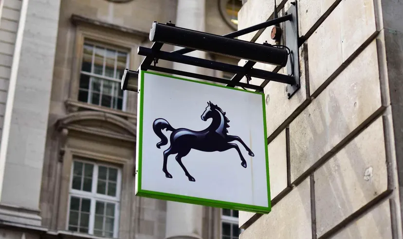 Lloyds Bank black horse logo displayed on a hanging sign outside a stone building, representing the British banking and financial services group.