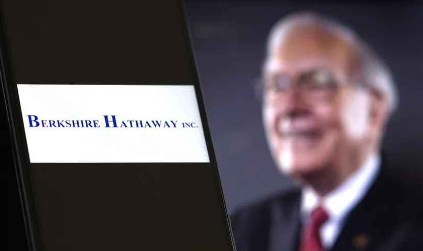 Logo di Berkshire Hathaway in primo piano con Warren Buffett sfocato sullo sfondo, simbolo della strategia prudente della holding rispetto al mercato azionario USA Logo di Berkshire Hathaway in primo piano con Warren Buffett sfocato sullo sfondo, simbolo della strategia prudente della holding rispetto al mercato azionario USA