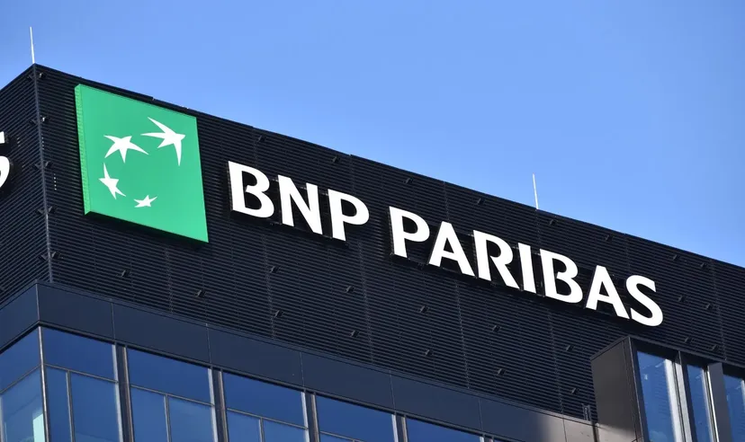 Logo BNP Paribas affiché sur la façade d'un immeuble de bureaux moderne sous un ciel bleu dégagé