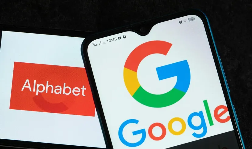 Ein Smartphone zeigt das Google-Logo vor einem Bildschirm mit dem Alphabet-Unternehmenslogo