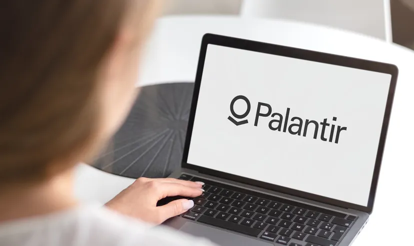 Person using a laptop displaying the Palantir logo on the screen