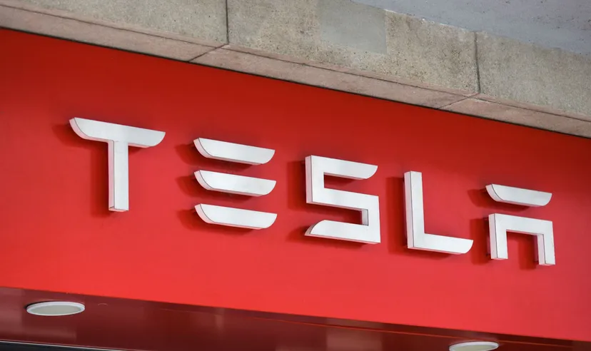 Tesla logo displayed on a red storefront sign mounted on a building exterior
