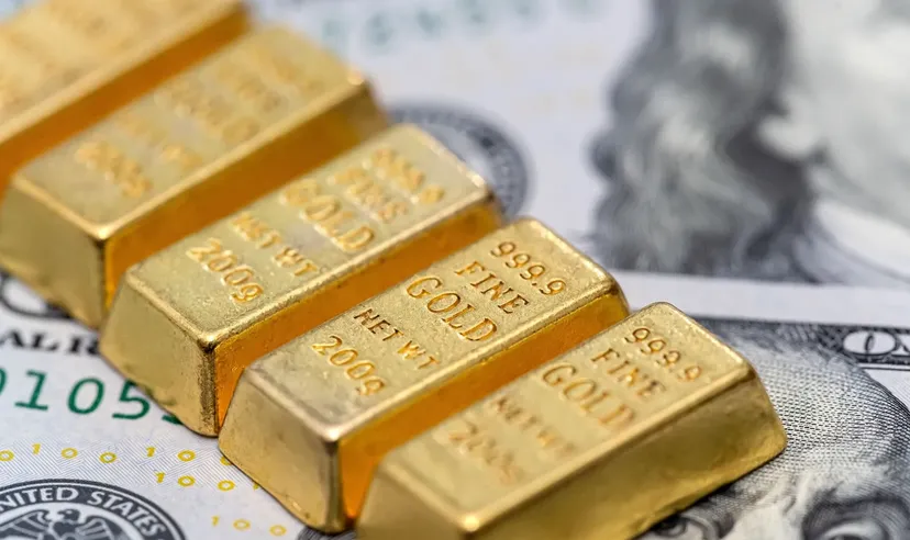 Gros plan de plusieurs petits lingots d'or marqués « 999.9 Fine Gold 200g » posés sur des billets de banque en dollars américains