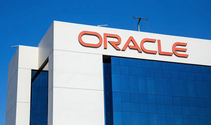 Oracle logo displayed on the exterior of a modern office building with blue glass windows under a clear sky. 