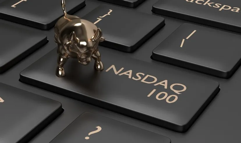 A key on a computer keyboard adapted to say NASDAQ 100, with a small gold bull charm sitting on it 