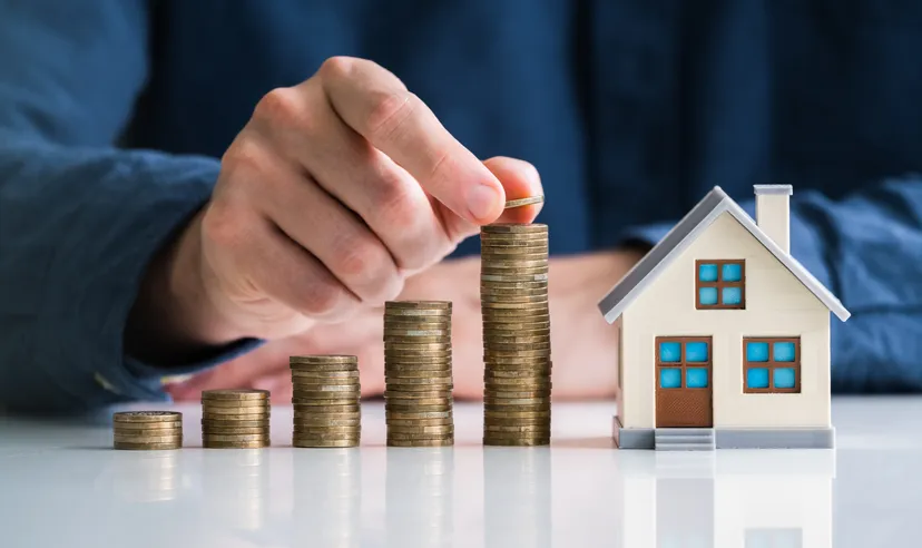Representation of increasing stacks of coins next to a model house