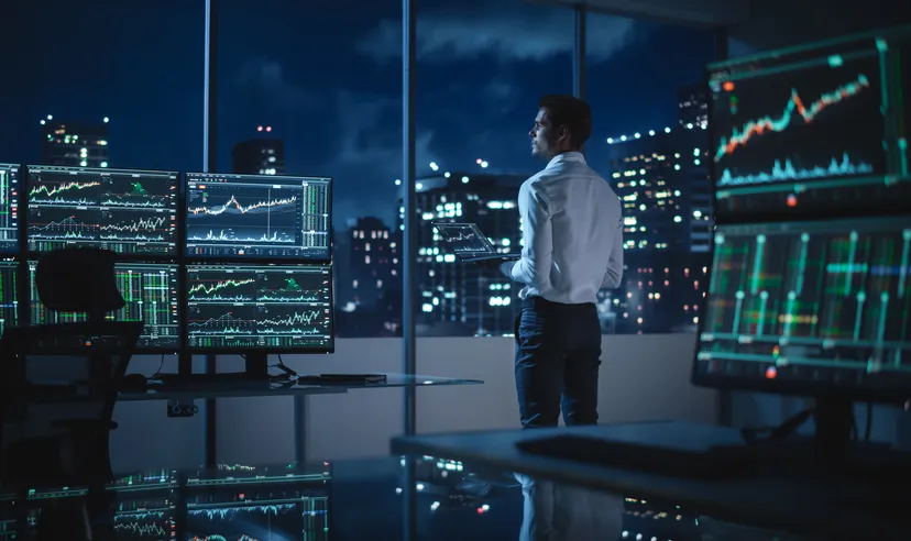 A financial trader surrounded by multiple screens