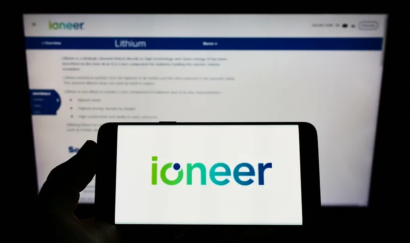 Person holding mobile phone with logo of Australian mining company company ioneer Ltd on screen in front of web page Focus on phone display
