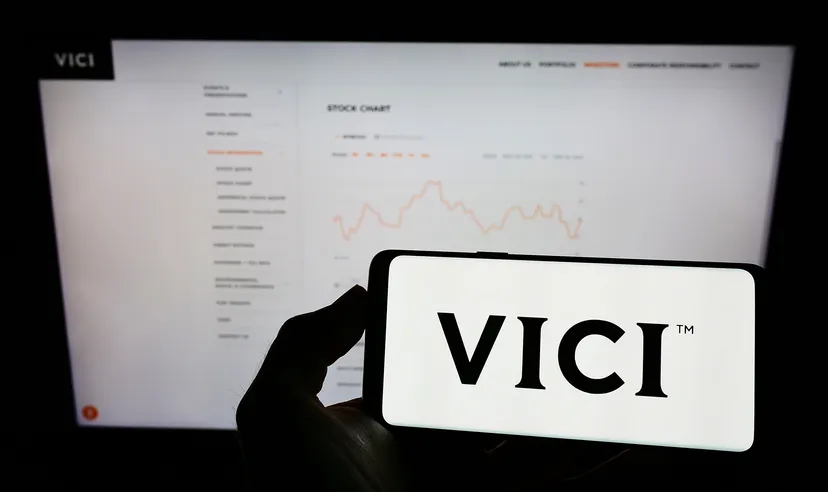 Person holding cellphone with logo of US real estate company Vici Properties Inc. on screen in front of business webpage. Focus on phone display