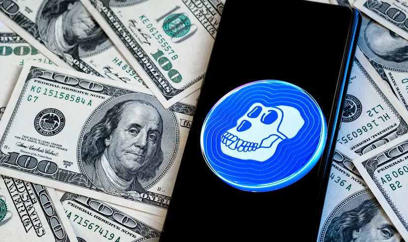 Apecoin logo on a smartphone screen with piles of US dollars in the background