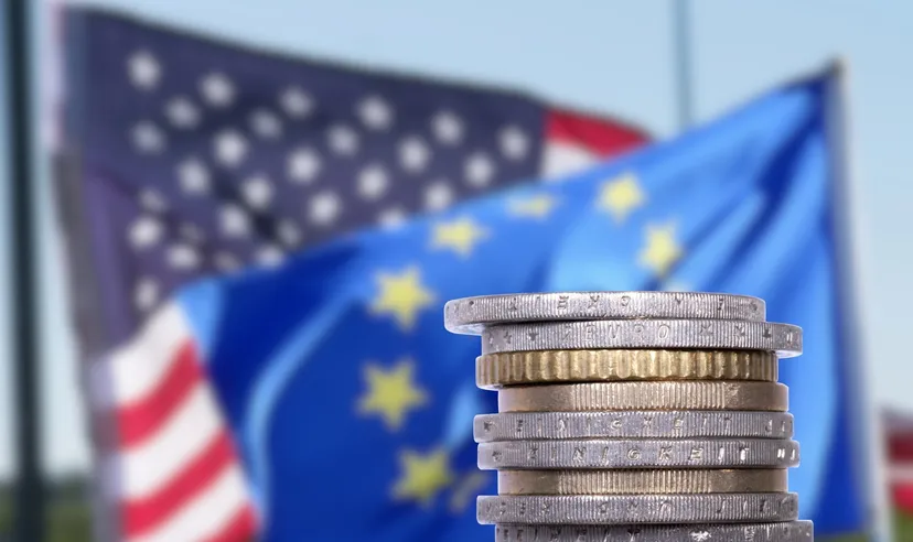 Bandiere di USA e Unione Europea con monete in primo piano, simbolo delle decisioni sui tassi di interesse di Fed e BCE