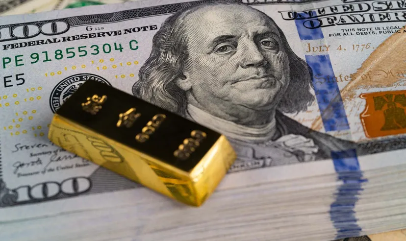 Lingotto d'oro posizionato su banconote da $100 dollari USA