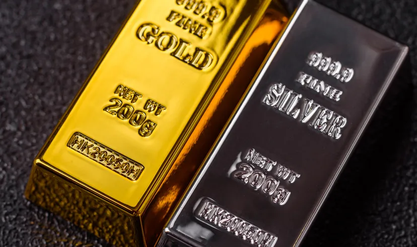 Lingotti d'oro e d'argento da investimento su sfondo scuro.