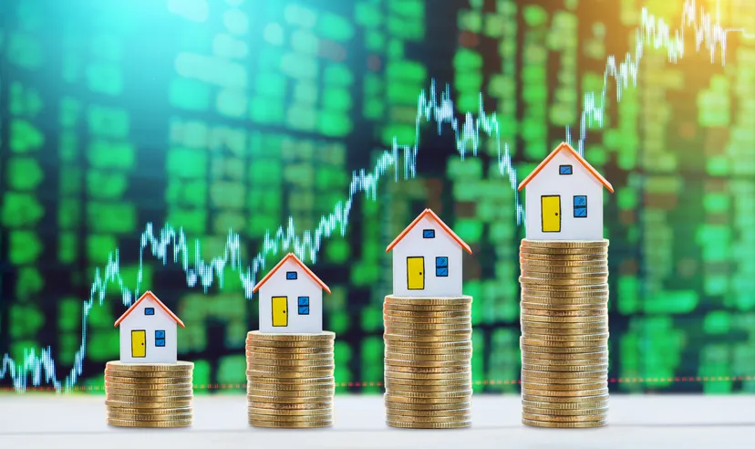Model houses and coins on table representing finance