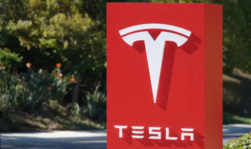 Tesla logo displayed on a red sign outdoors