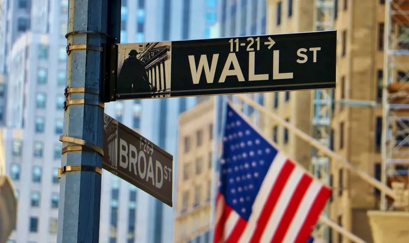 Znak Wall Street z amerykańską flagą i budynkami miasta w tle