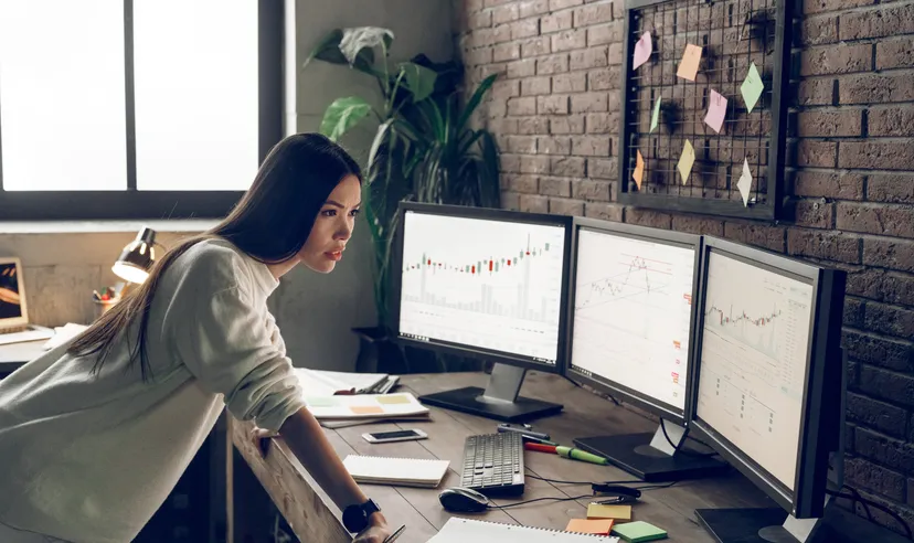 Female trader at a desk with market screens