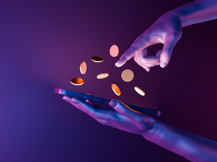Cryptos A hand hovers over a smartphone as coins jump out of its screen